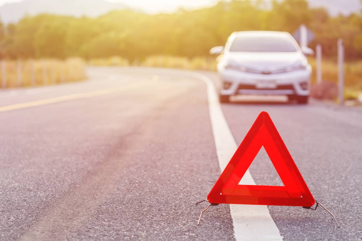 car broken down on side of road with warning sign