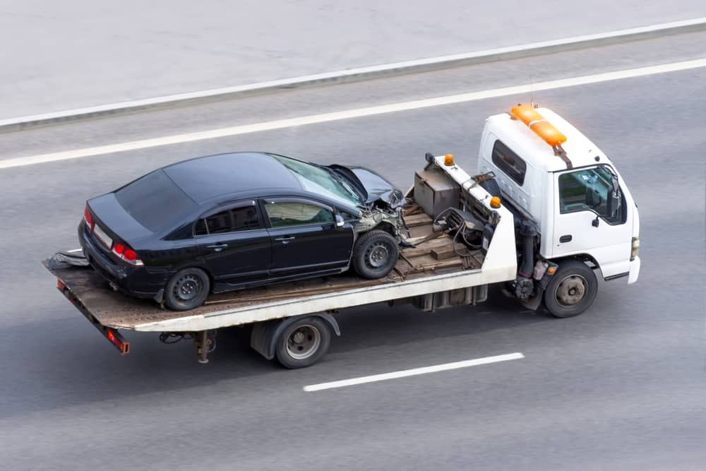 Wrecked car after an accident on a tow truck transported on a highway